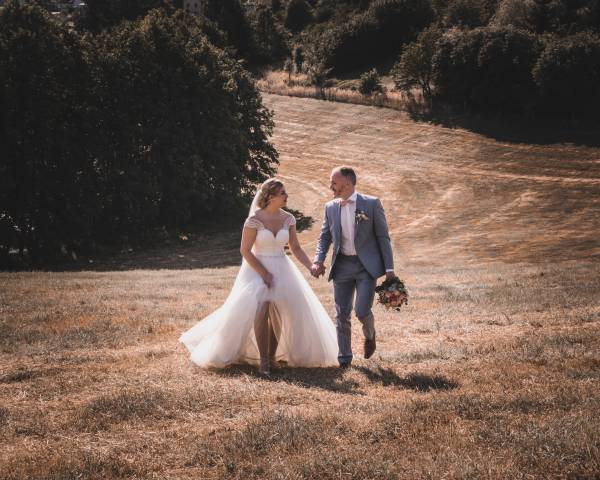 Brautpaar läuft über ein Feld